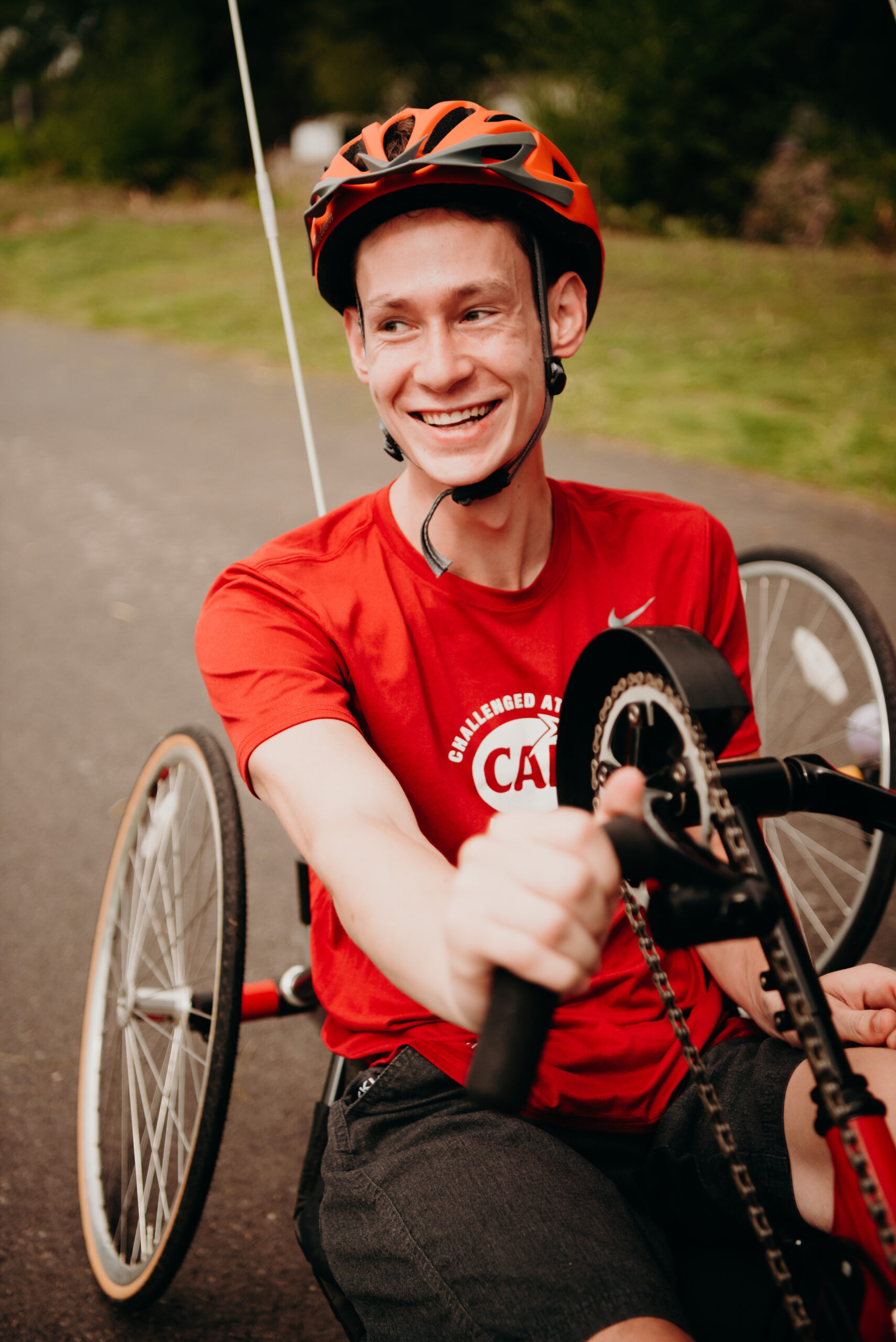 Hustle participant Camron Gabler on a handcycle bike in a red shirt smiling